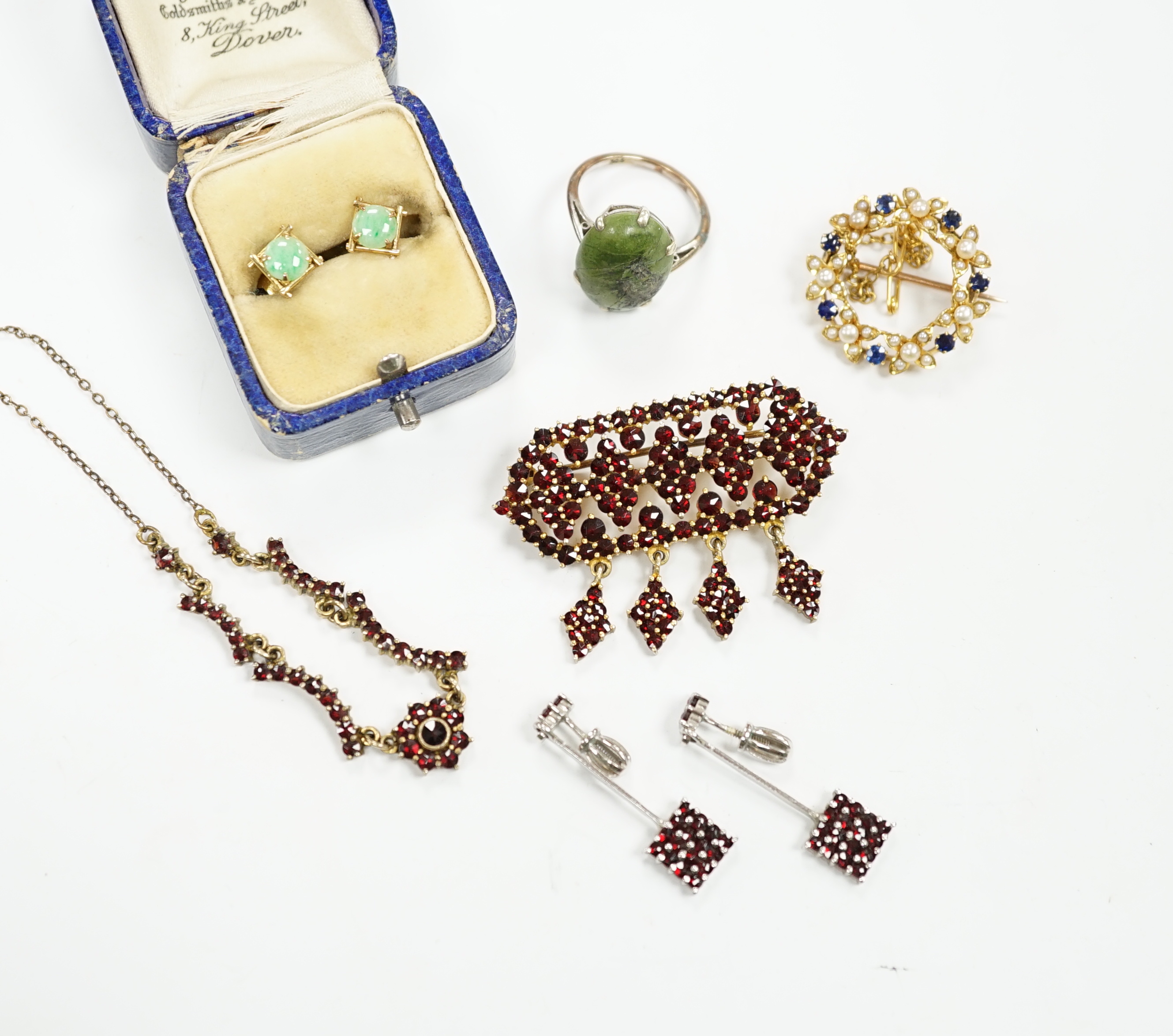 A yellow metal, sapphire and seed pearl cluster set openwork brooch, 23mm, a 9ct and hardstone ring, four items of garnet set jewellery and a pair of jade set ear studs.